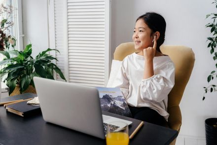 Smiling girl attending online school from home, using a laptop and headphones.
